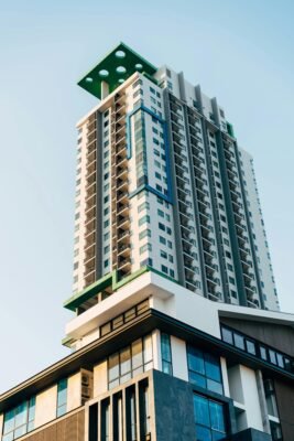 Modern high-rise building with unique design against clear blue sky, low angle view.