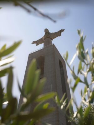 View of Cristo Rei statue framed by leaves, Lisbon's iconic landmark.